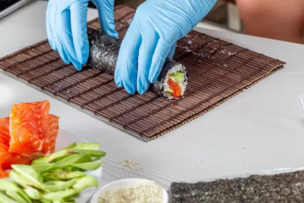 Chef hands in disposable gloves cooking sushi at kitchen of home (Flip 2019)