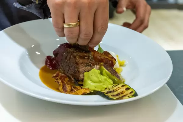 Chef prepares a good-looking meal with meat, vegetables and creme, cooked with WMF kitchen aids