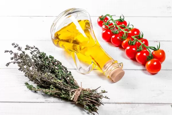 Cherry tomatoes branch, fresh thyme with olive oil on white wooden background