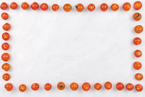 Cherry tomatoes frame on the grey marble table