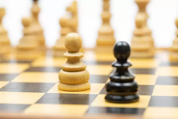 Chess figures on the chess board with black pawn in the focus