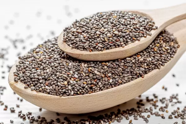 Chia seeds in wooden spoons on wooden table