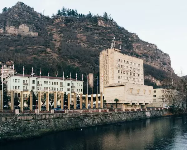 Chiatura cityhall: a prominent example of stalinist architecture overlooking a river with cliffs in the background