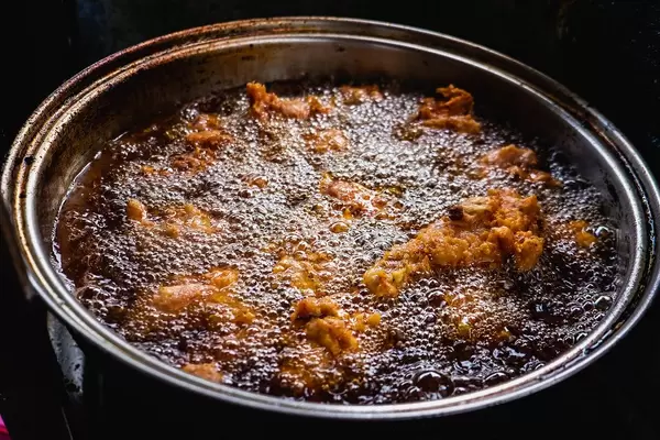 Chicken being cooked in a deep fry pot