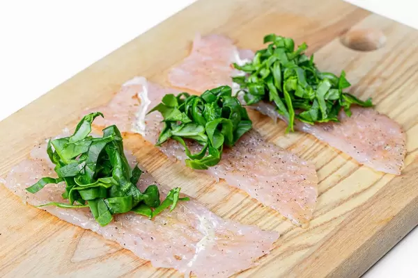 Chicken chops and chopped spinach on the kitchen Board (Flip 2019)