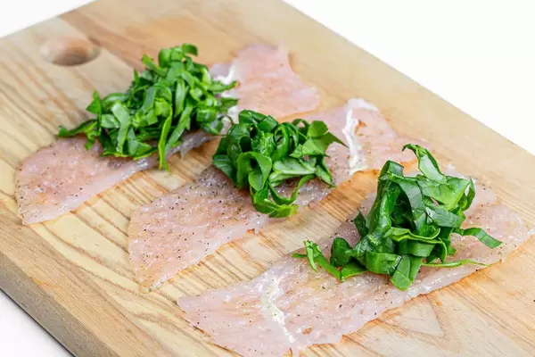 Chicken chops and chopped spinach on the kitchen Board