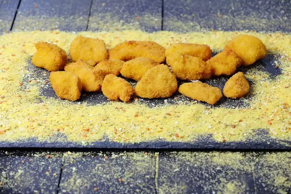 Chicken Nuggets Stücke aus Hähnchenfleisch, vor einem dunklen Hintergrund
