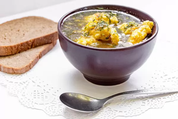 Chicken soup with dumplings, pieces of black bread with a spoon