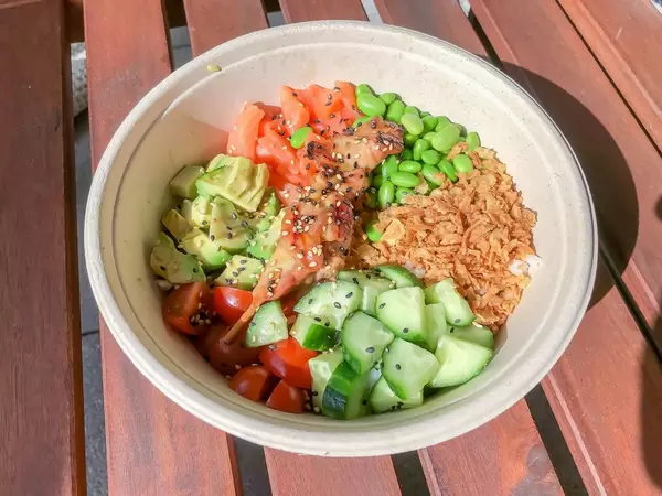Chicken Teriyaki mit Avocado, Tomaten, Saubohnen, Rostzwiebel, Sushireis und Gurken in einer weißen Schale von Eat Simple
