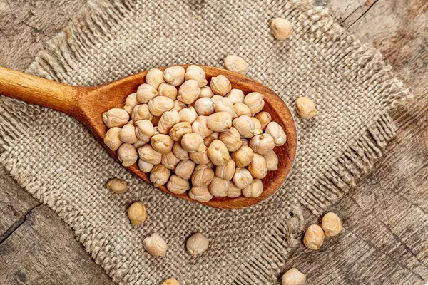 Chickpeas in a wooden spoon on burlap. Top view