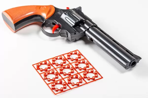 Children's pistol with cartridges on a white background (Flip 2020)