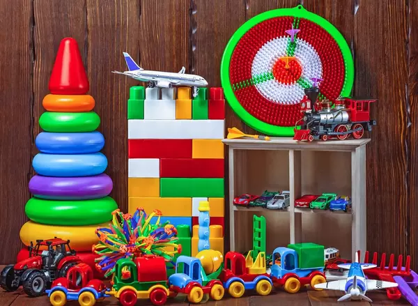 Children's values: toys, pyramid, darts, cars, train on a wooden background