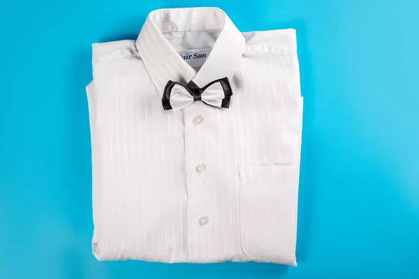 Children's white shirt with bow tie on blue, top view