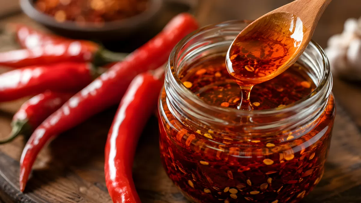 Chiliöl im Glas mit frischen roten Chilischoten
