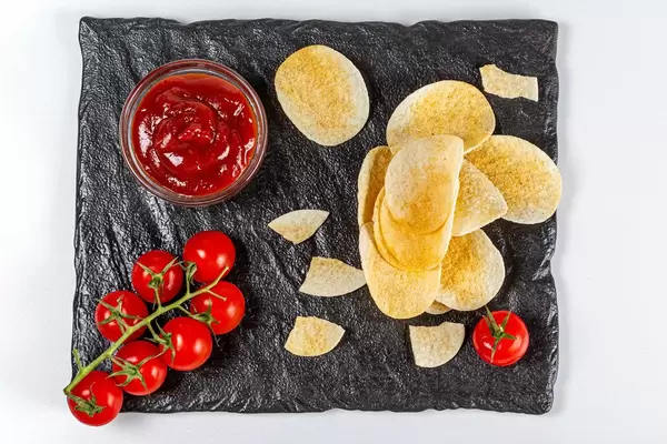 Chips and ketchup with tomato, top view