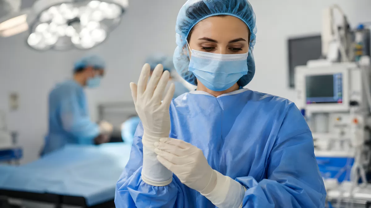 Chirurgin zieht Operationshandschuhe im OP-Saal an