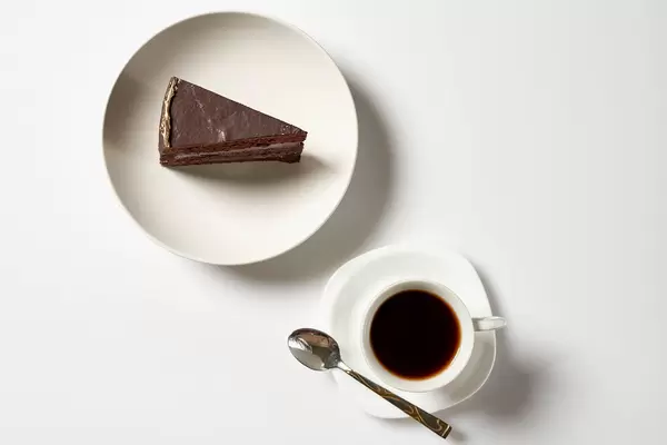 Chocolate cake slice with coffee mug on white background