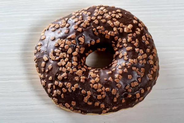Chocolate donut on white wooden background close-up