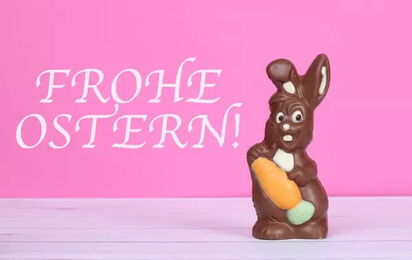 Chocolate easter bunny with Frohe Ostern text on pink background