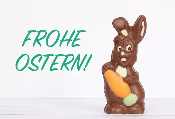 Chocolate easter bunny with Frohe Ostern text on white background
