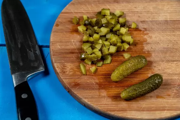 Chopped Pickles on the round wooden board with knife