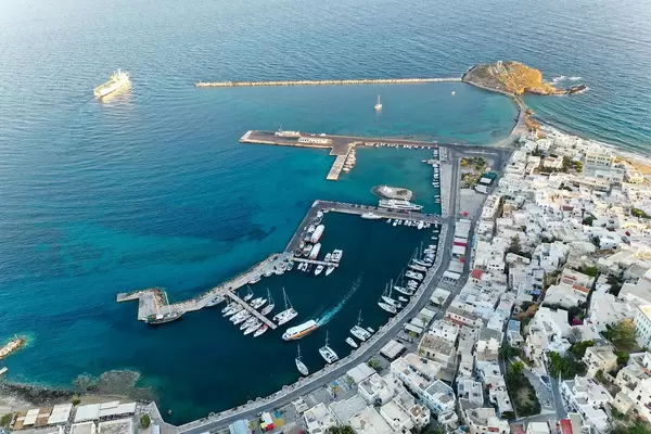 Chora, Naxos, with its port, a cargo ship leaving, and the Portara on the islet Palátia. Aerial shot of the city