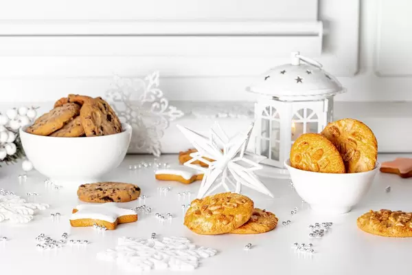 Christmas background with different cookies, decor and lantern with burning candles