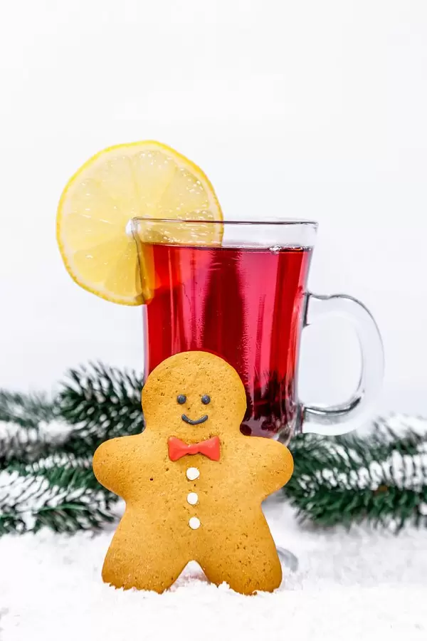 Christmas background with mulled wine and snow-covered Christmas tree branches and gingerbread man