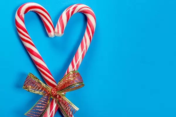 Christmas candy canes heart shaped on blue background