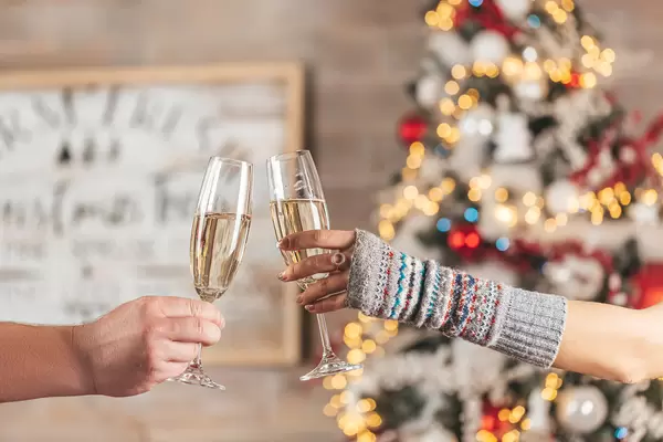 Christmas celebration background with two glasses of champagne in the hands of a man and a woman