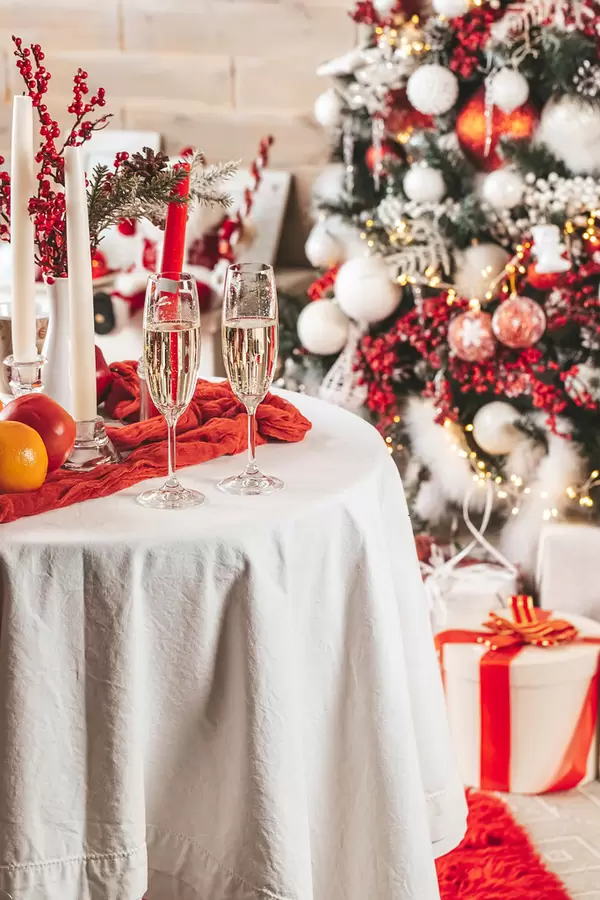 Christmas composition - two glasses with champagne on table near a christmas tree in beautifully decorated room