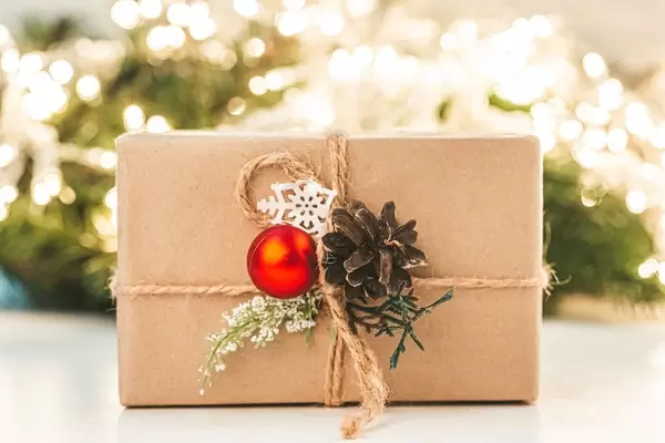 Christmas gift on a blurred background of a glowing garland and branches of a Christmas tree