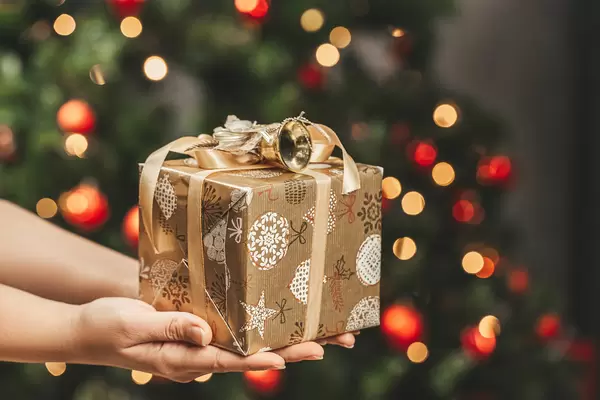Christmas greeting background with a gift in the hands of a girl