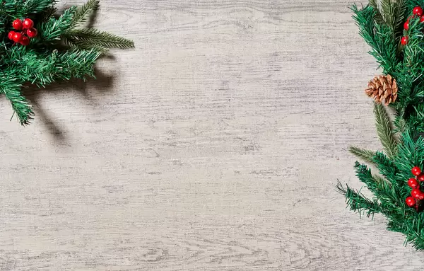 Christmas holiday background with evergreen pine branches and red berries over wood background