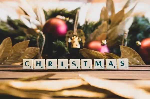 CHRISTMAS mit Scrabble Buchstaben geschrieben mit Weihnachtsdekorationen im Hintergrund