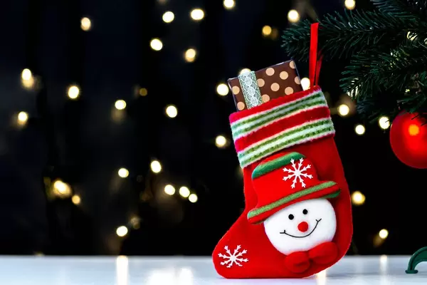 Christmas sock with a gift on a blurry background of luminous garlands (Flip 2019)