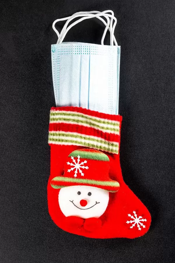 Christmas sock with masks inside on black. Coronavirus concept and winter holidays