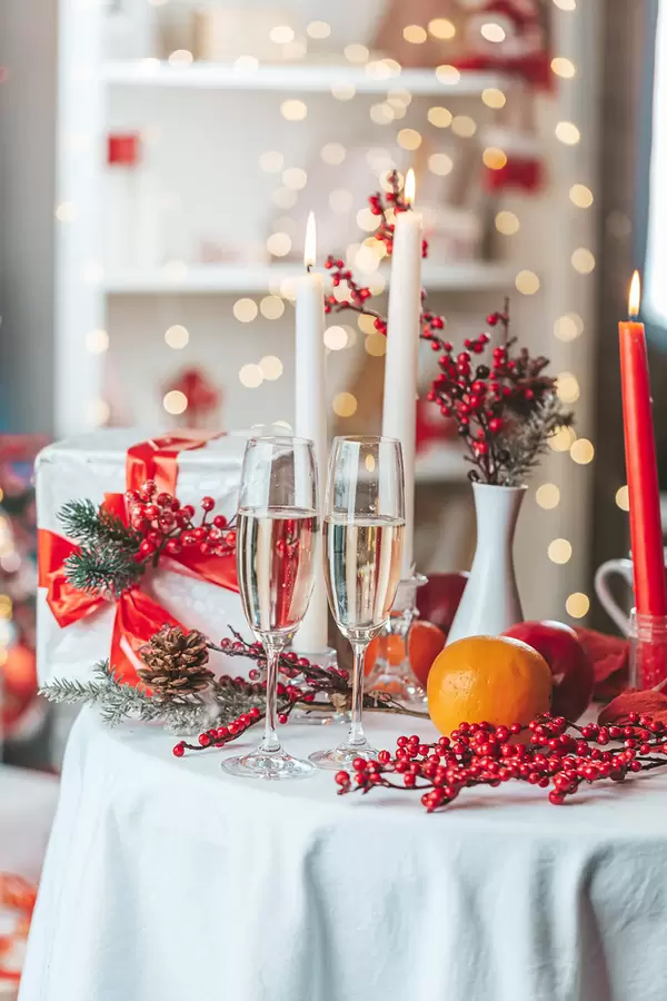 Christmas table with champagne, candles and a gift in a decorated living room