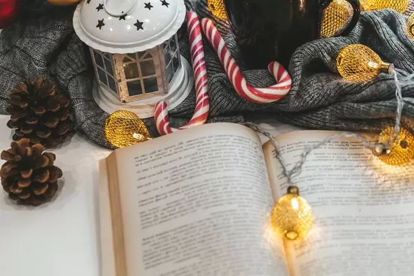 Christmas tale concept-open book with garland, lantern and candy lollipops (Flip 2019)