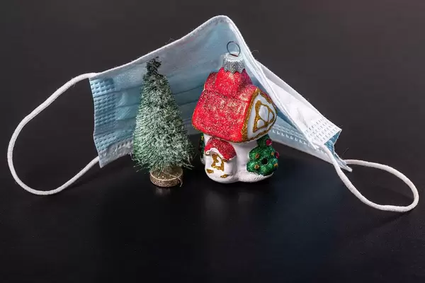 Christmas toys tree and house covered with medical mask on black background