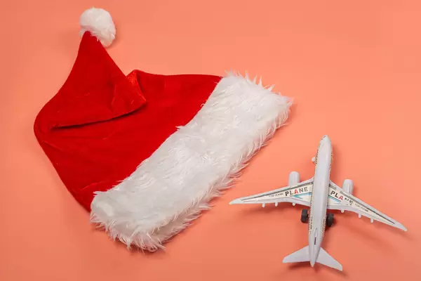 Christmas travel concept - santa hat and airplane on pink background