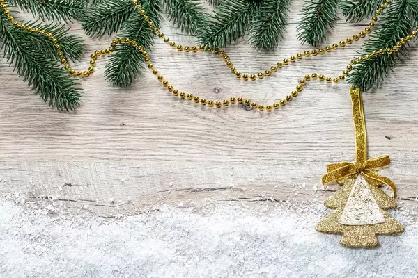 Christmas tree branches, snow and golden Christmas decor on wooden background (Flip 2019)