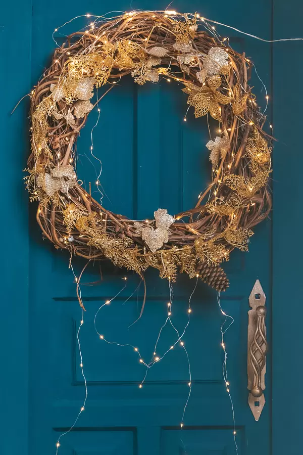 Christmas wreath with a luminous garland on a blue door