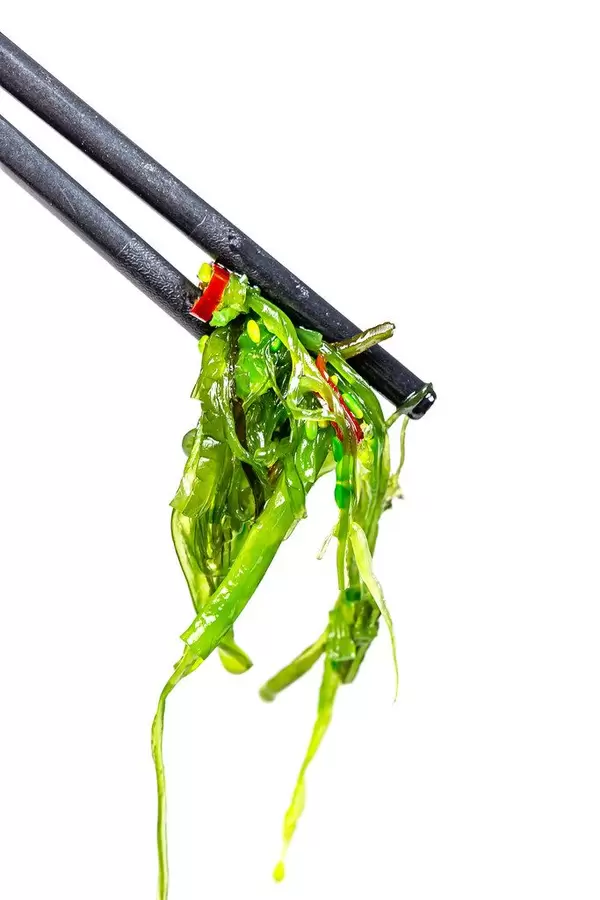 Chuka salad with sauce, sesame and chili on chopsticks