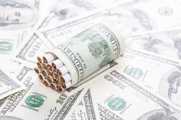 Cigarettes wrapped in a dollar on a background of money
