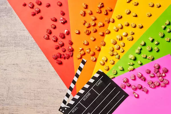 Cinema evening with tasty popcorn and clapboard on wooden background