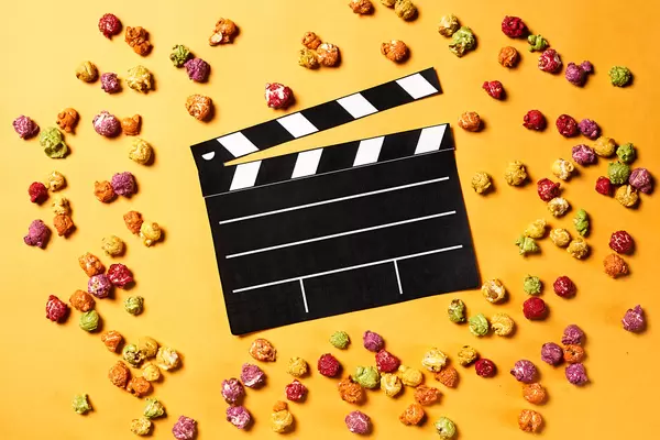 Clapper board with popcorn on yellow background. Cinema concept