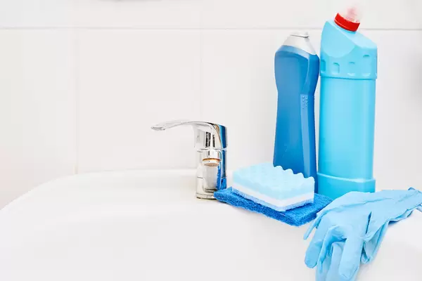 Cleaning supplies on washing basin in modern bathroom