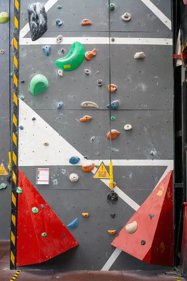 Clip In Warning Sign Before Climbing next to a Rope clipped in an Anchor on a Wall in an Indoor Climbing Hall