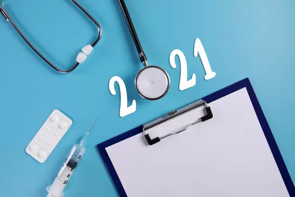 Clipboard, stethoscope, syringe and pills with 2021 text on blue background